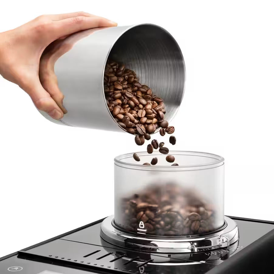 Hand pouring coffee beans into a coffee grinder on a white background