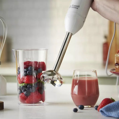 Russel Hobbs Stick Hand Blender blending mixed berries in a measuring cup next to a glass of smoothie