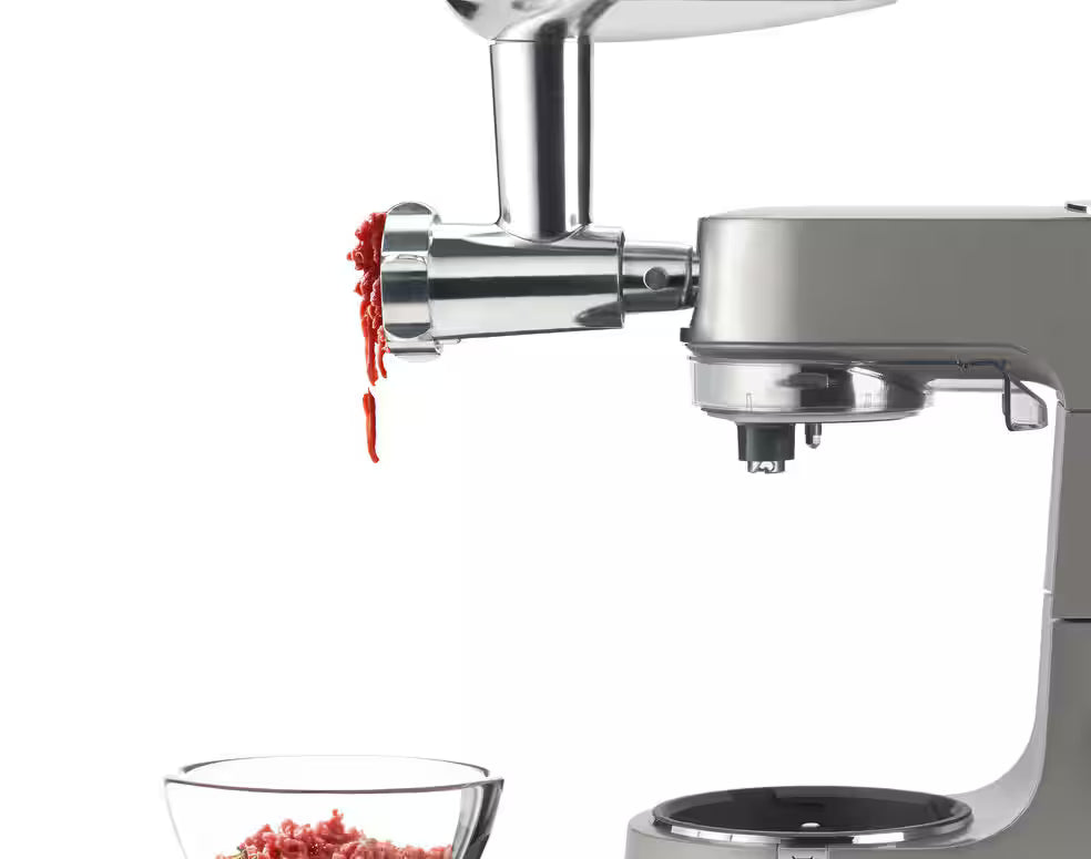 Kenwood KAX950ME meat grinder attachment on stand mixer, grinding fresh meat into a bowl below.