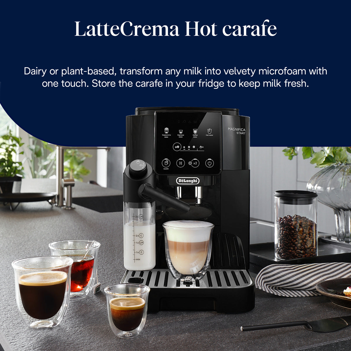 DeLonghi Magnifica Start coffee machine with milk frother, layered latte, espresso shots, and coffee beans jar on counter.