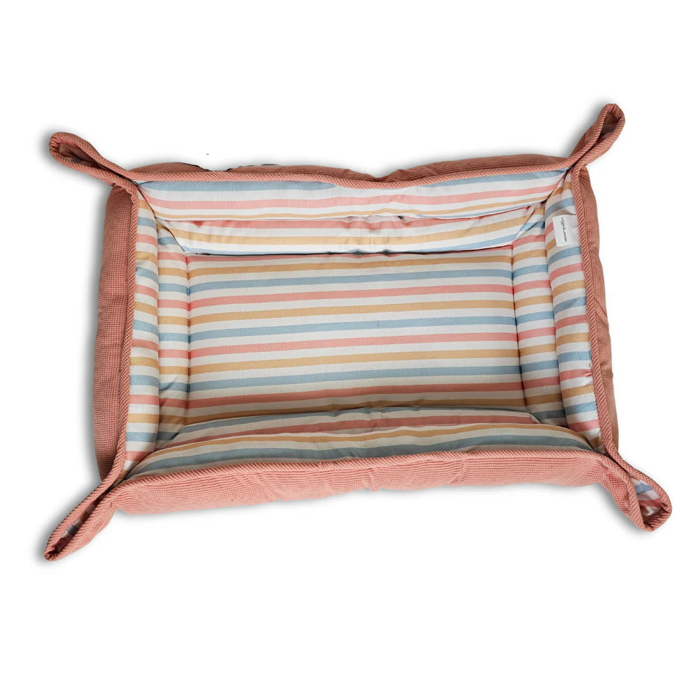Rectangular pink pet mat bed with multicolored horizontal stripes and raised edges with looped corners.
