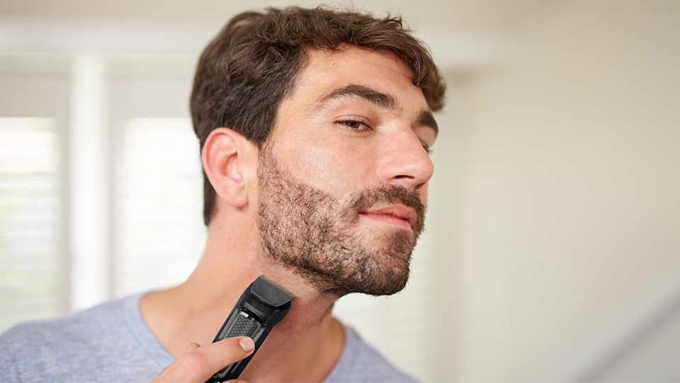 Philips Multigroom Series 3000 trimmer grooming a man's beard and neck hair at an angle.