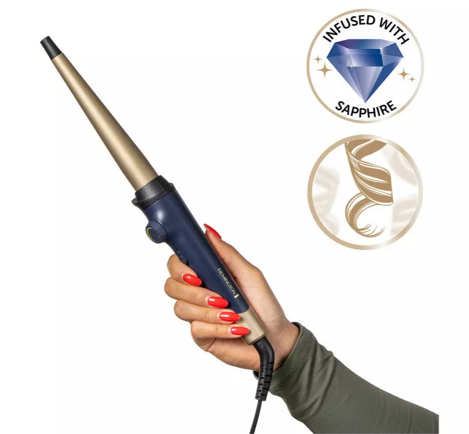 Hand holding Remington Sapphire Curling Wand with tapered gold barrel and navy handle on white background.