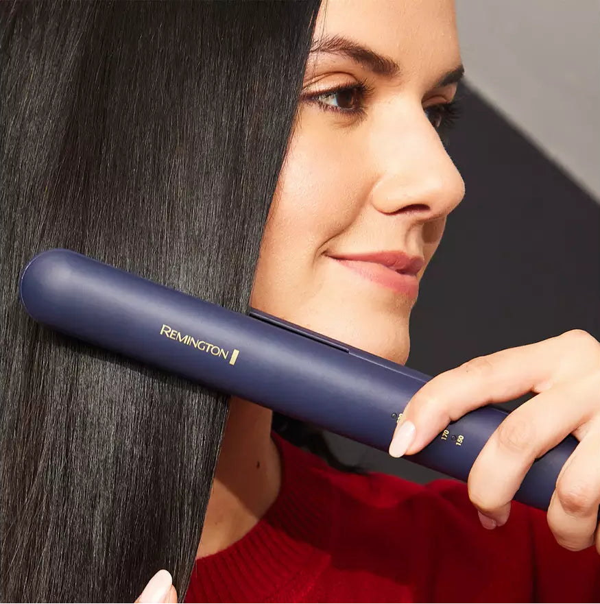 Woman using Remington Sapphire Hair Straightener on long, straight black hair, close-up side view.