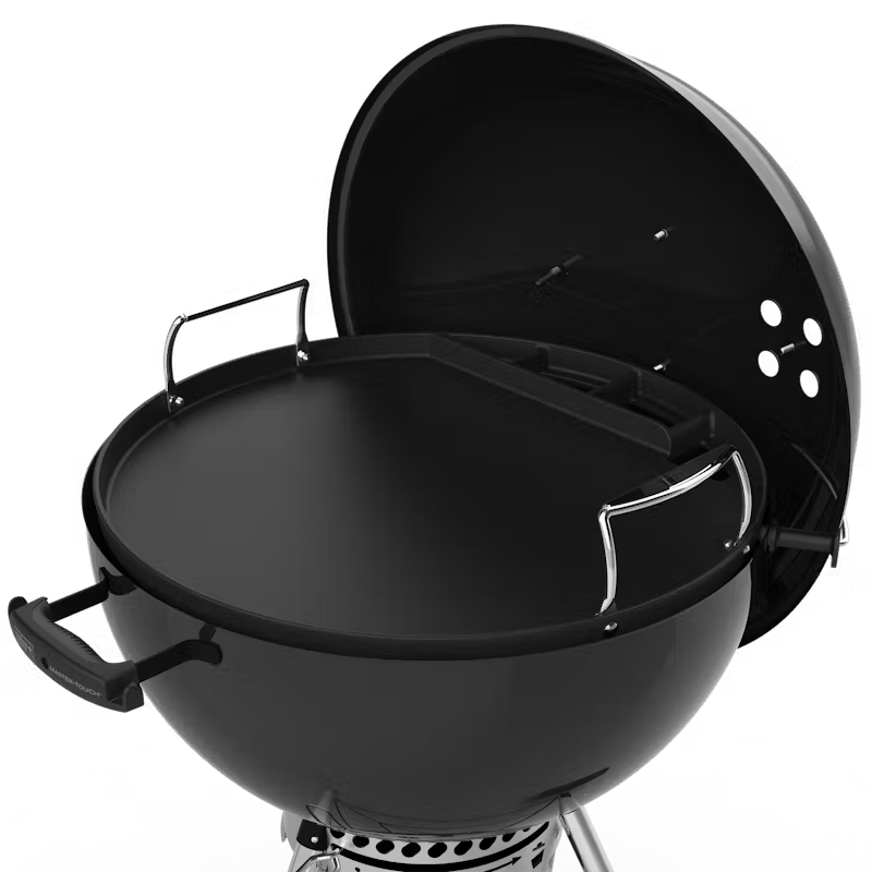 Weber full-size black griddle on a 57cm kettle grill with lid open and side handles visible