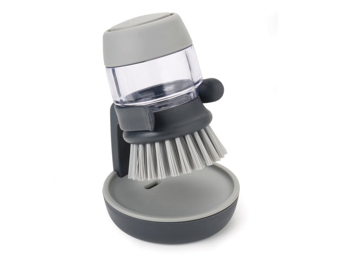 Grey Joseph Joseph Palm Scrub brush with refillable detergent, ergonomic grip, and stand – available at Keans Claremorris.