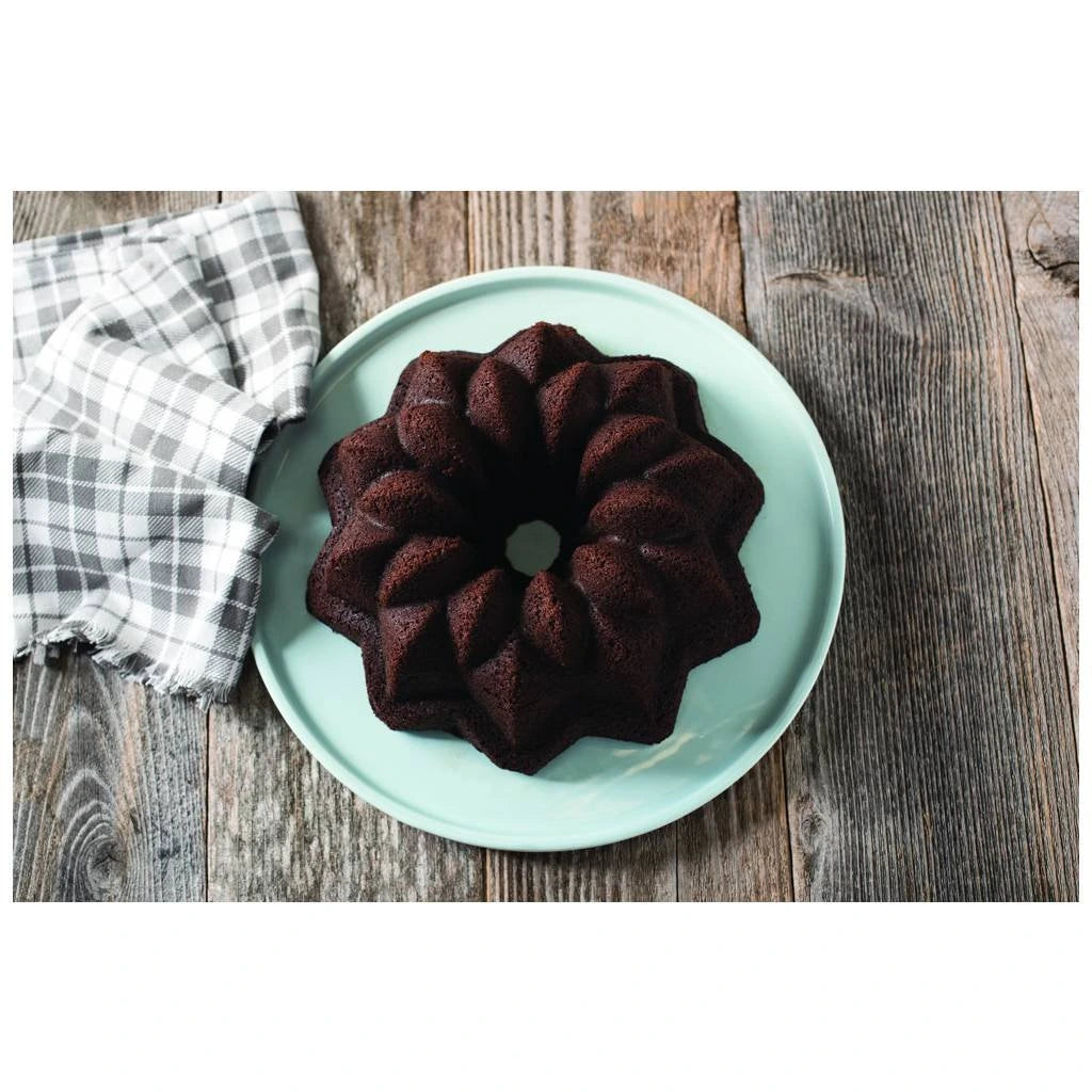 Chocolate cake shaped in a star pattern on a light blue plate with a gray checkered cloth on wooden surface
