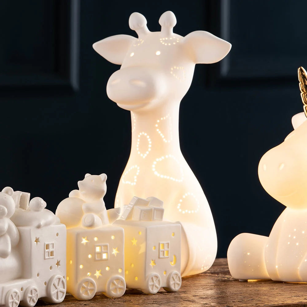 Luminaire Giraffe LED glowing softly with light patterns on a wooden surface against a dark background.