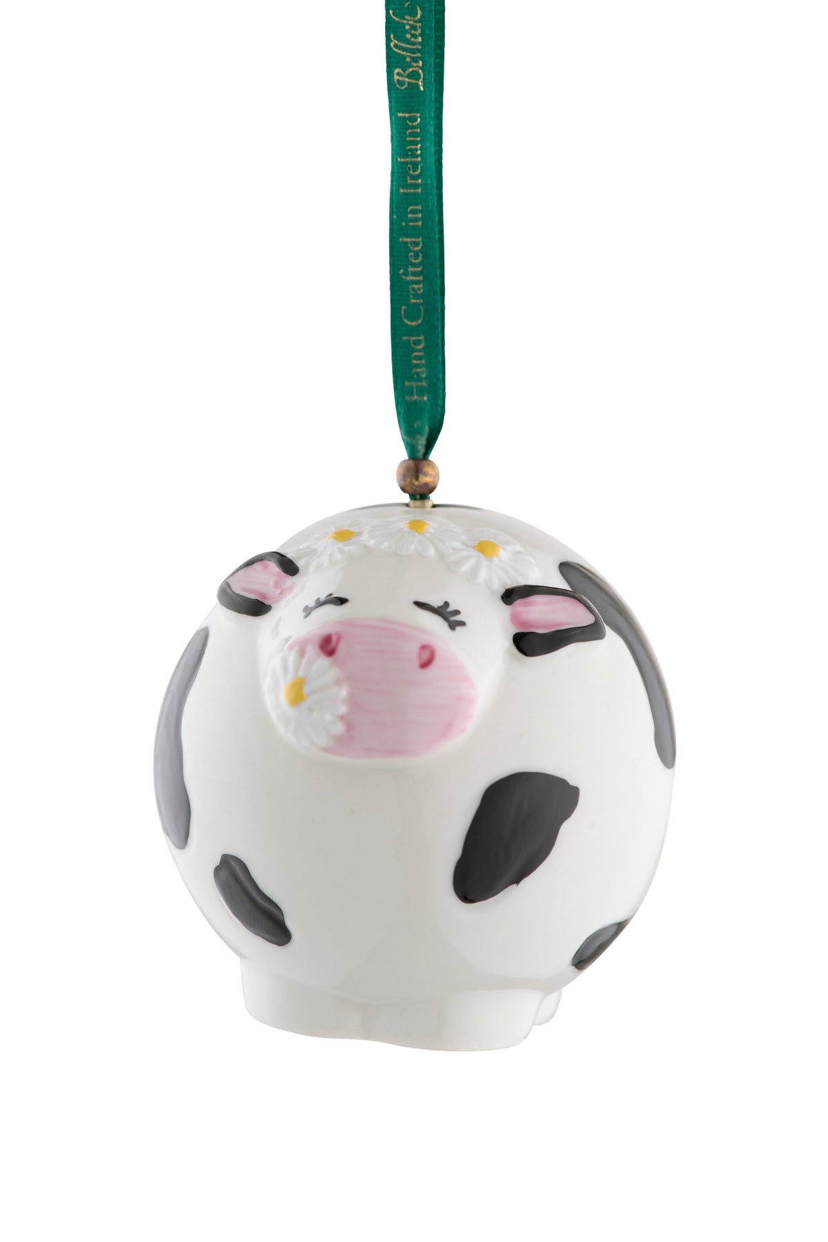 Round white ceramic cow ornament with black spots, pink snout, daisies on head, and green hanging ribbon.