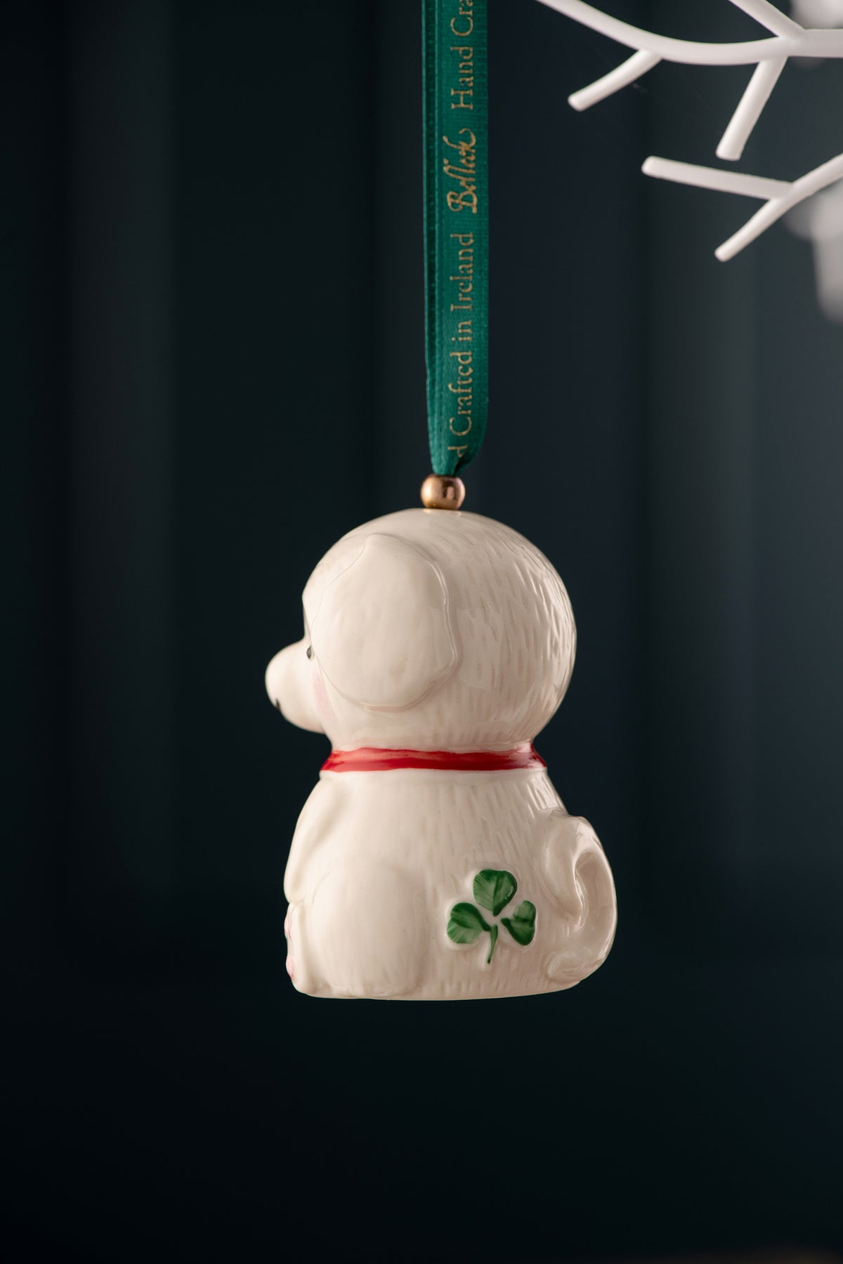 Side view of Belleek Classic Doggy Ornament showing white dog with red collar and green shamrock on its side hanging by