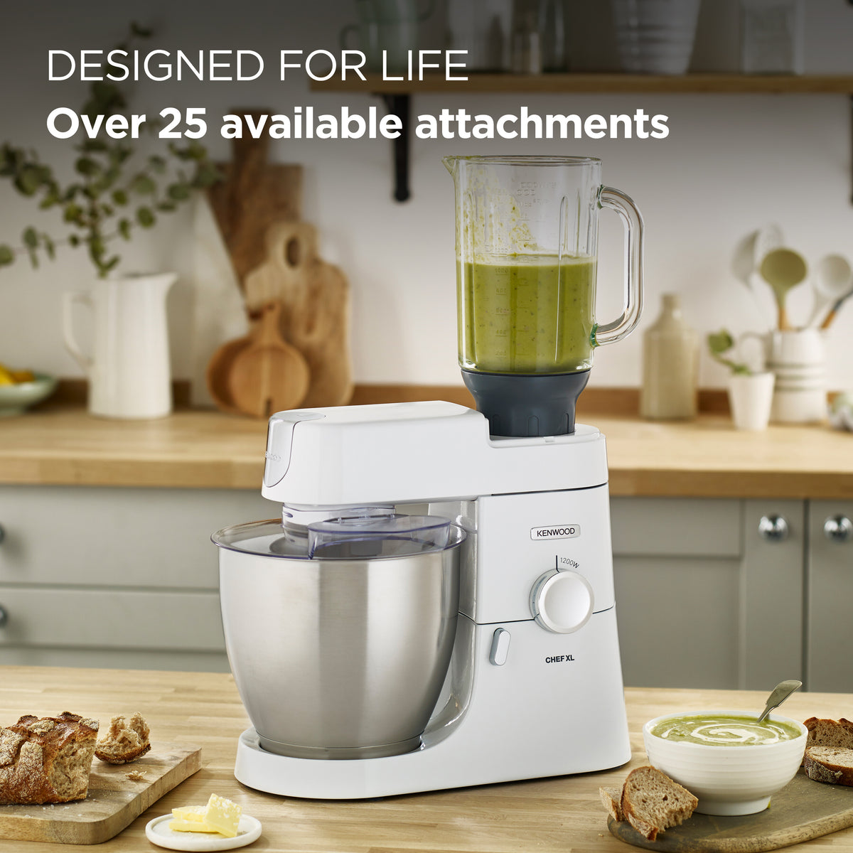 Kenwood Chef Mixer XL with stainless steel bowl and blender attachment on wooden kitchen counter with bread and soup.