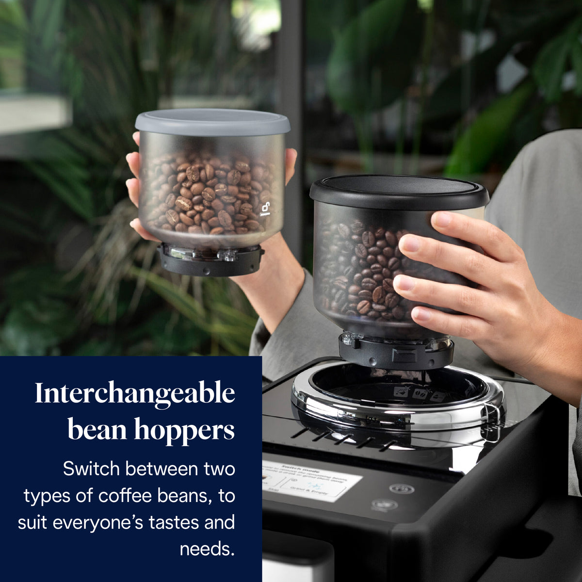 Hands holding two interchangeable bean hoppers filled with coffee beans above a DeLonghi coffee machine.