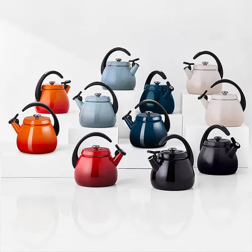 Ten Le Creuset Cloche Kettles in various colors including red, black, blue, orange, and beige, arranged on white blocks.