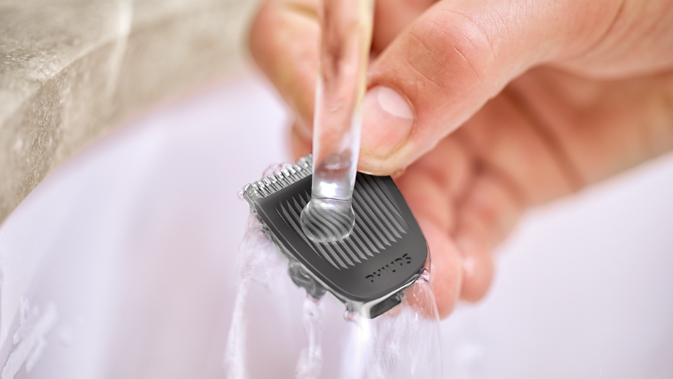 Close-up of Philips Multigroom 3000 trimmer head being rinsed under running water.