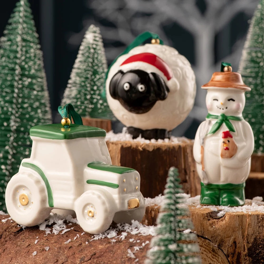 Sheep ornament with black face and red Santa hat, displayed on wood with festive decorations.