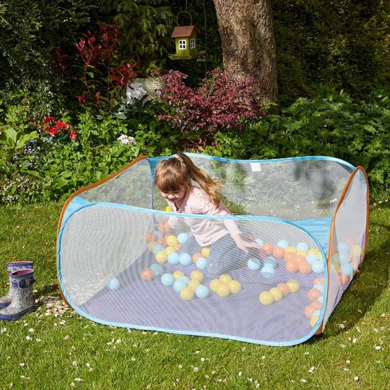 Child playing inside a blue mesh Pop-Up PlayPit filled with colorful playballs on grass outdoors