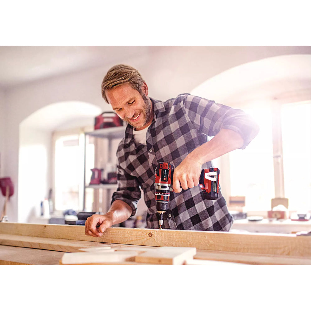Man using Einhell PXC Professional Brushless Combi Drill on wood in a bright workshop setting