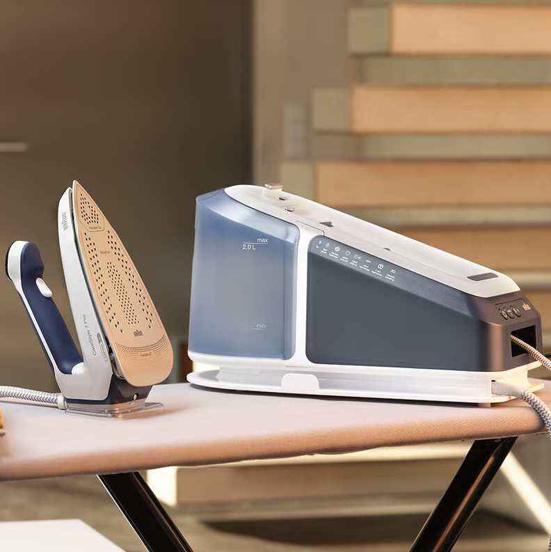 Braun Steam Generator Iron with beige soleplate and blue water tank on ironing board in a home setting