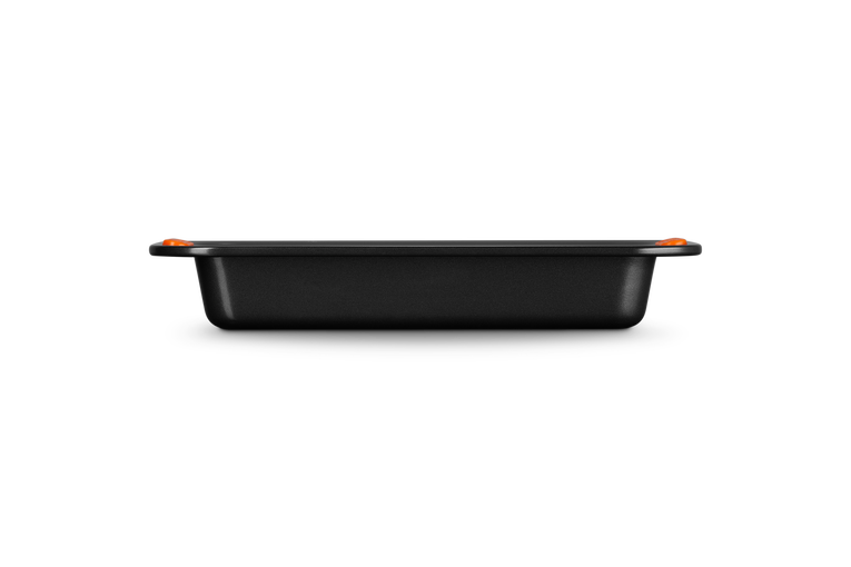 Le Creuset rectangular 33cm cake tin in black with orange silicone handles, side view.