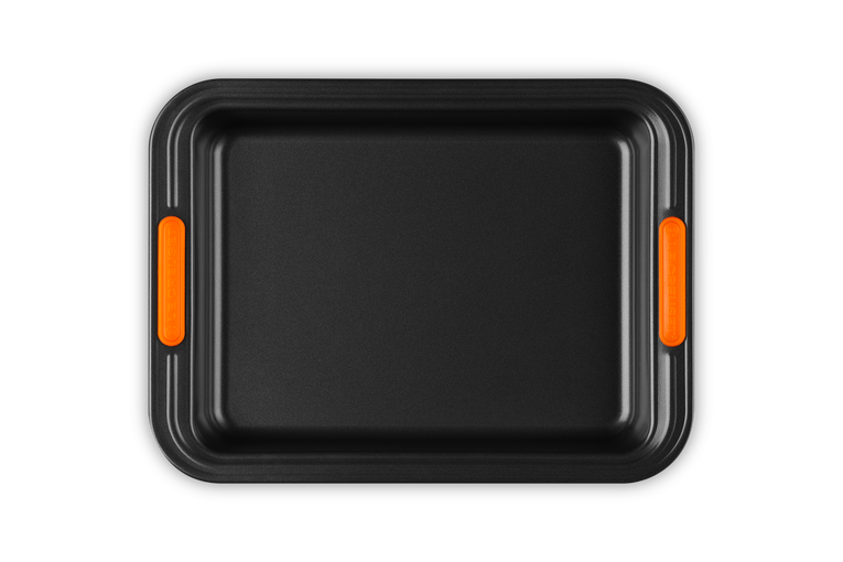 Le Creuset rectangular 33cm cake tin in black with orange silicone grip handles, top view.