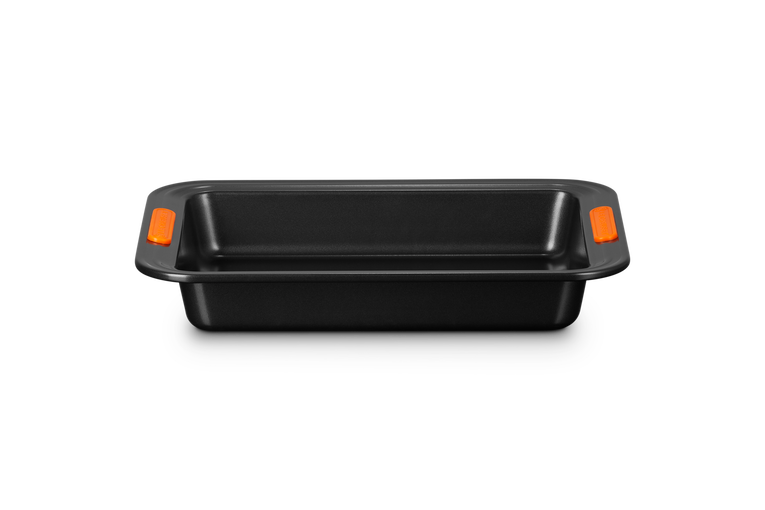 Le Creuset rectangular cake tin with non-stick coating and orange heat-resistant silicone handles.