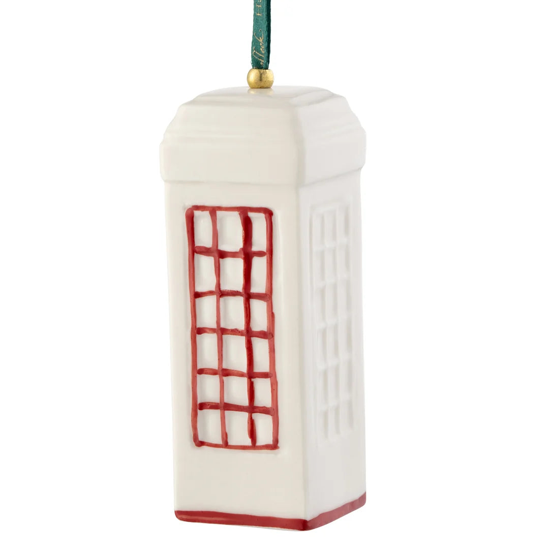 White ceramic ornament shaped like a red telephone box with red window and base details, hanging by a green ribbon.