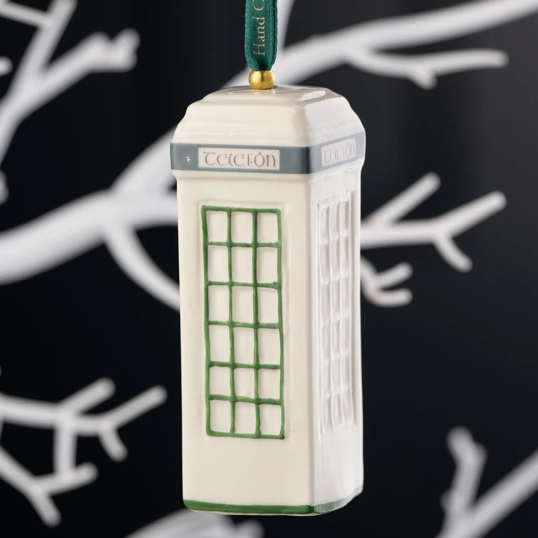 Cream ceramic Classic Irish Telefón Box ornament with green window panes hanging on a green ribbon against a black