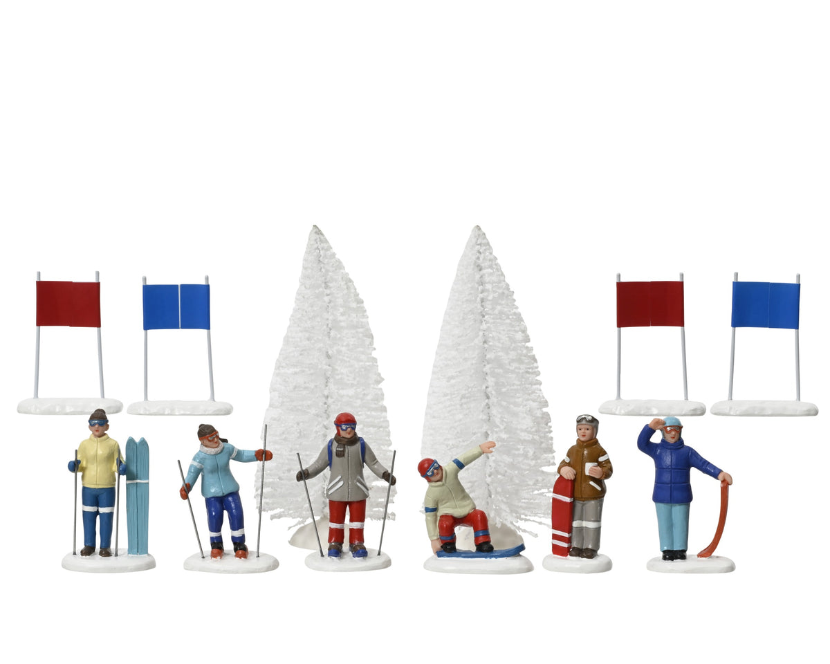 Miniature ski and snowboard figurine set with six figures, two snow-covered trees, and four red and blue flags on white