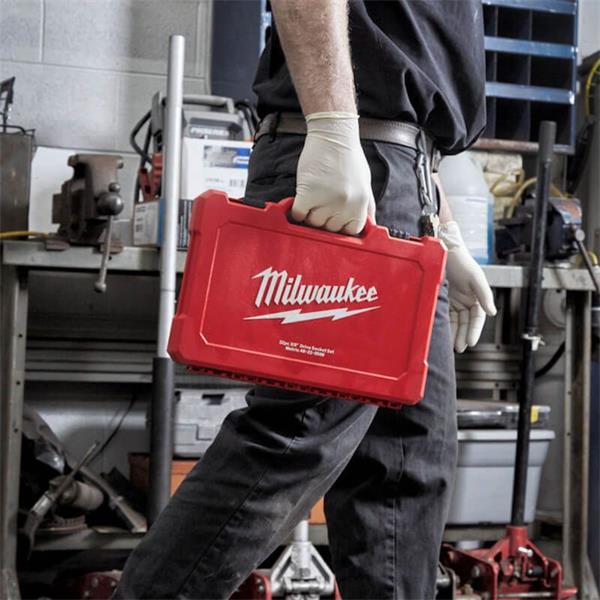 Person wearing gloves carrying a red Milwaukee tool case for 1/4" driver ratchet and socket set in a workshop
