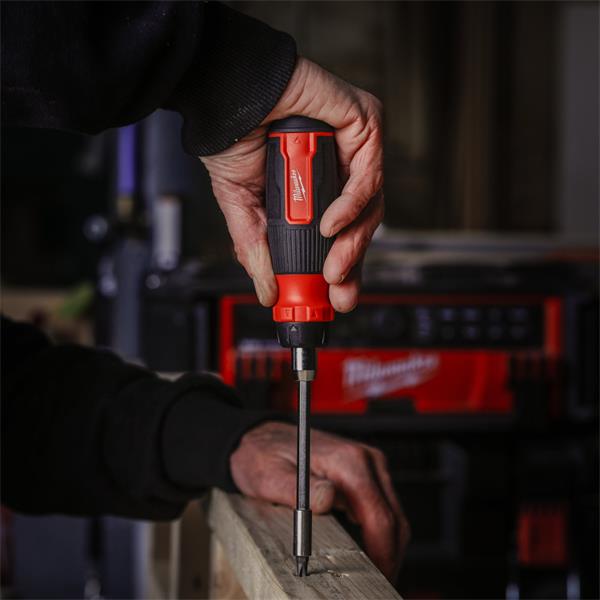 Hand using Milwaukee 27 in 1 Ratchet Multi-Bit Screwdriver to drive a screw into wood.