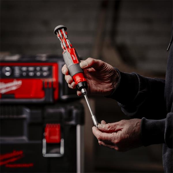 Hands holding a Milwaukee 27 in 1 ratchet multi-bit screwdriver with bits stored in the handle.