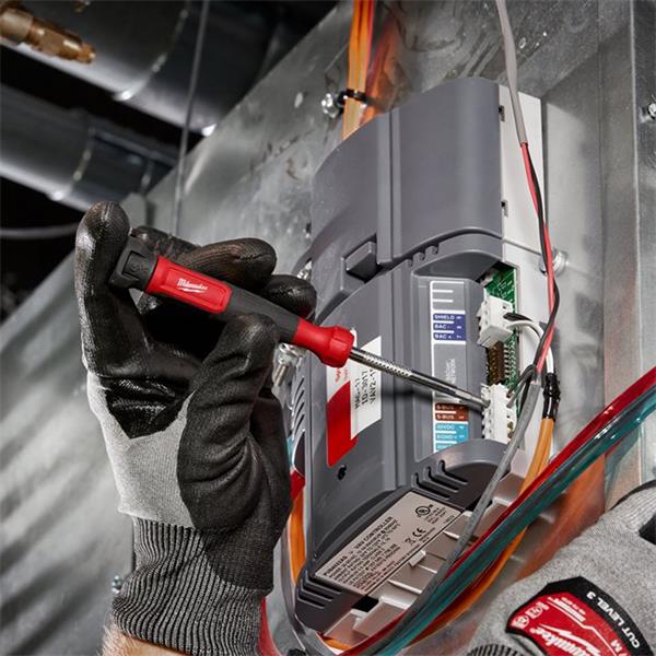Hand with glove using Milwaukee 4 in 1 Precision Multi-Bit Screwdriver to adjust wiring on electrical panel