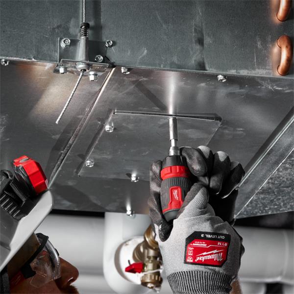 Hands wearing gloves using Milwaukee ratchet multi-bit screwdriver to tighten screws on metal panel.