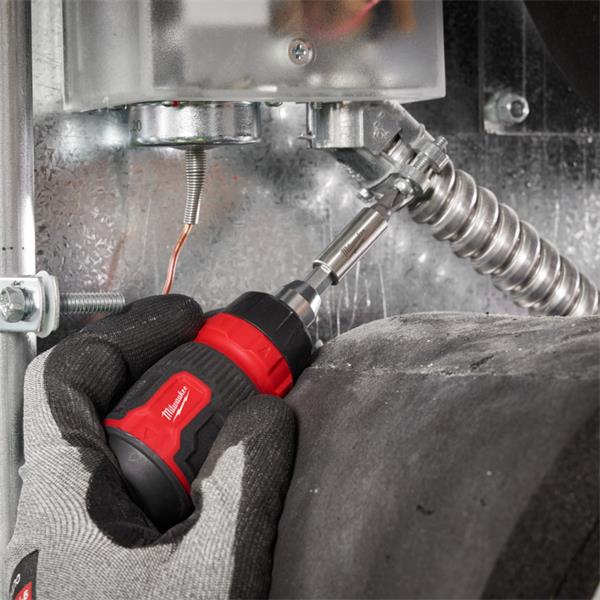 Hand wearing glove using Milwaukee ratchet multi-bit screwdriver to tighten metal conduit connection.