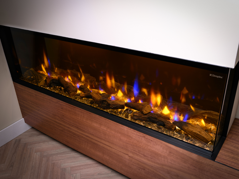 Dimplex Ignite Bold 60″ built-in electric fire with glowing logs and blue and orange flames in a modern wooden surround.