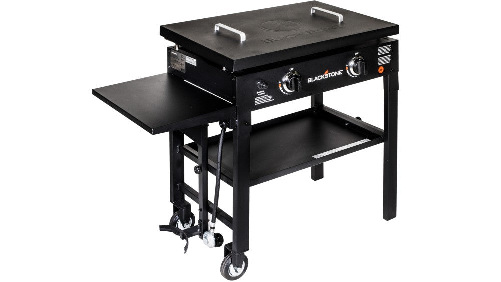 Blackstone 28'' Hard Cover griddle with closed lid, side shelf, control knobs, and caster wheels.