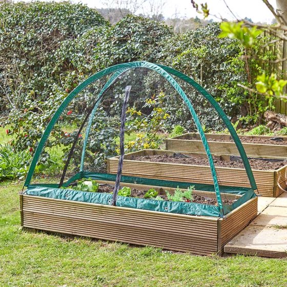 GroCage 1.8m x 0.9m wooden raised garden bed with green mesh protective cover in a backyard garden.