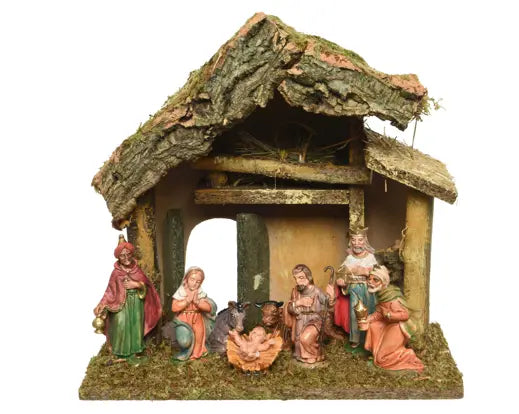 A traditional nativity scene figurine depicting the Holy Family, Three Wise Men, and a shepherd inside a rustic stable with a mossy, bark-textured roof, set against a plain white background.