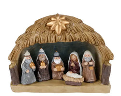 A nativity scene figurine set featuring a thatched-roof stable with six painted characters, including Mary, Joseph, baby Jesus in a manger, and three wise men, on a plain white background.