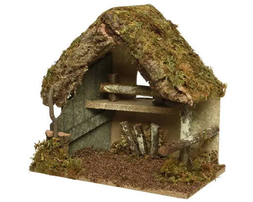 A miniature rustic thatched cottage or stable decoration with a mossy brown roof, weathered wood walls, and a textured base, isolated on a white background.