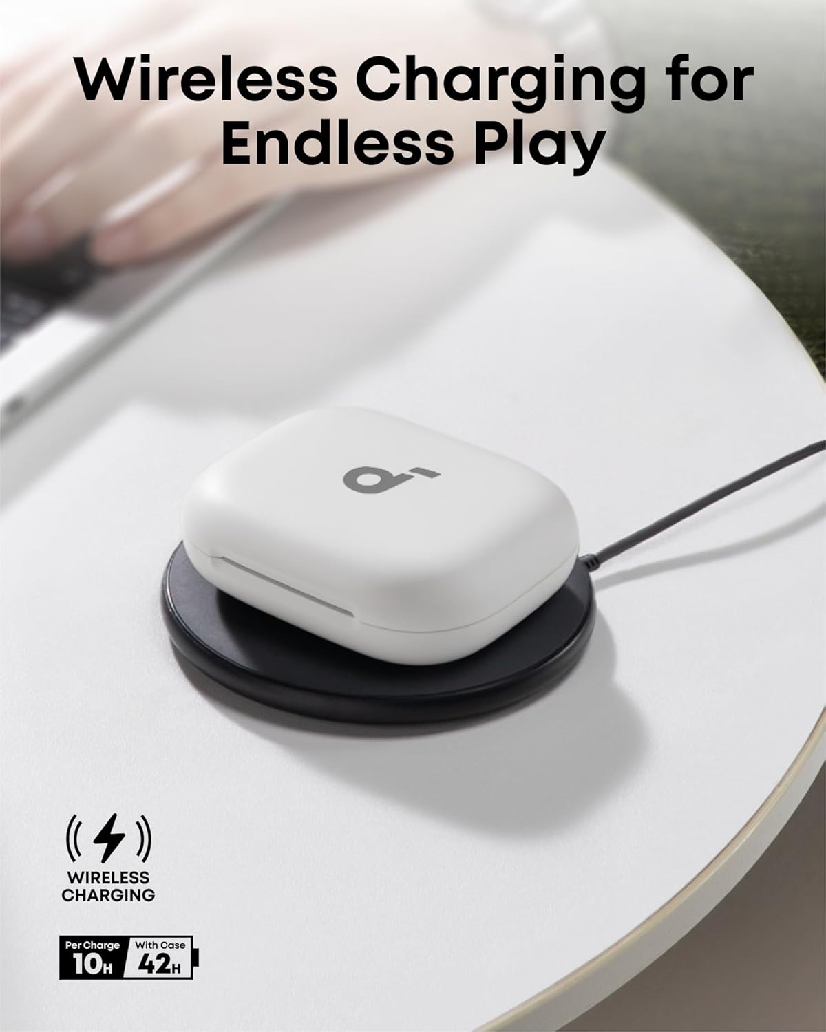White Soundcore AeroFit 2 earbuds charging case on a black wireless charging pad on a white table.