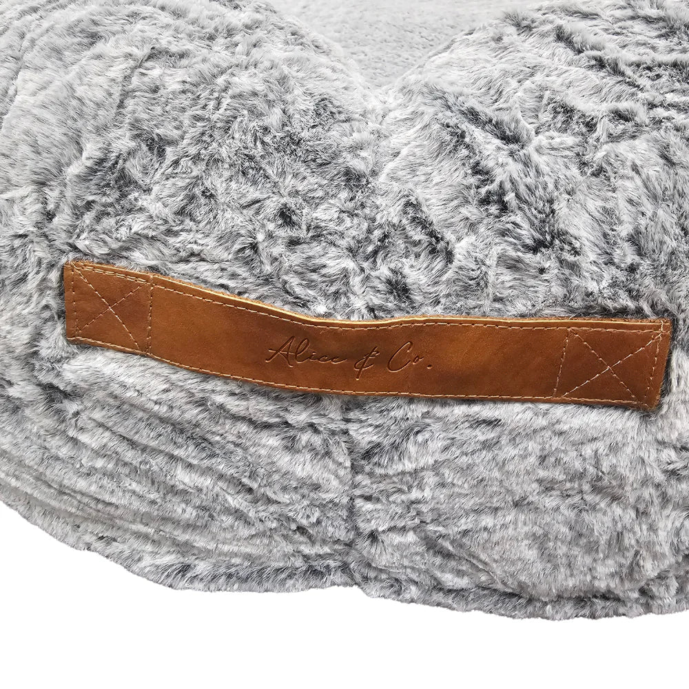 Close-up of grey faux fur fabric with a stitched brown leather handle labeled Alice & Co on the Beverley Bed.