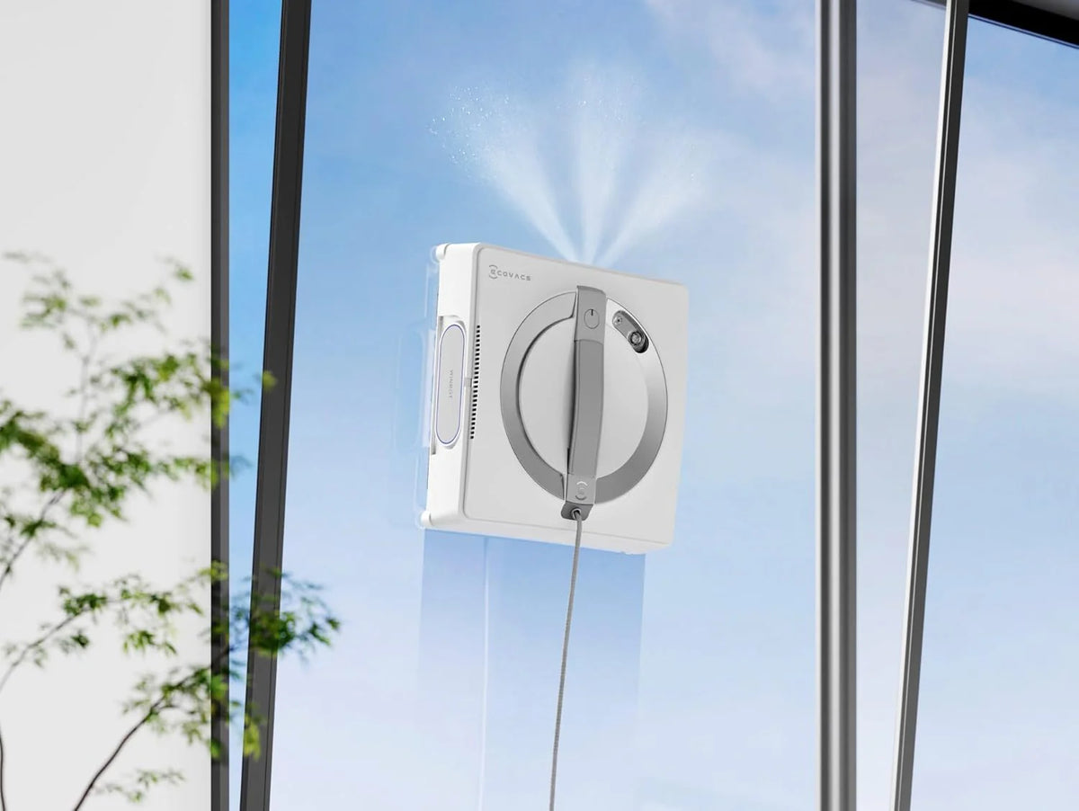 Ecovacs Winbot W2S Omni window cleaning robot spraying water on a glass window panel outdoors
