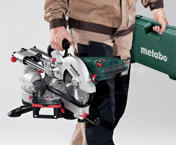 Person holding a Metabo 216mm Cross Cut Mitre Saw and a green Metabo carrying case