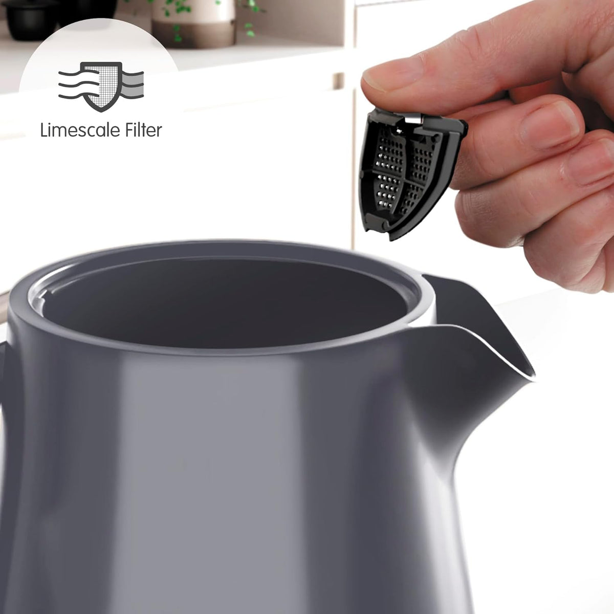 Hand holding limescale filter above the open spout of a grey Morphy Richards Hive Kettle.