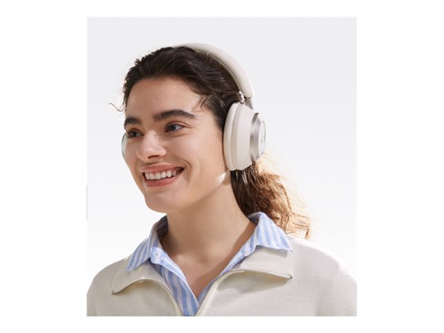 Woman smiling wearing white Soundcore Space One Pro headphones over her ears against a white background
