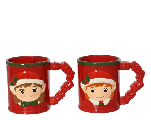 Two red ceramic Christmas mugs with sculpted handles shaped like pine branches and a green rim, each printed with a cartoon elf face wearing a Santa hat.