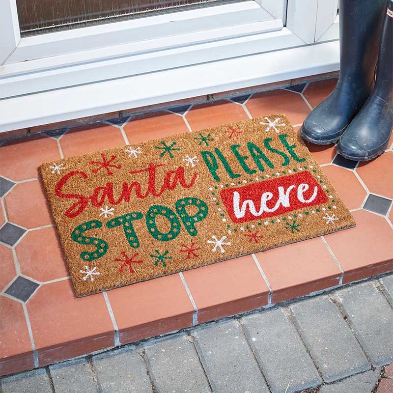 Santa Stop! Coir Door Mat 40x60cm with festive red, green, and white lettering on natural coir fibers by a doorstep.