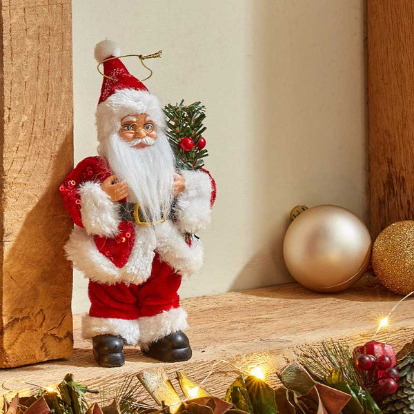 Decorative Santa Claus figure holding a small tree with Christmas decorations 