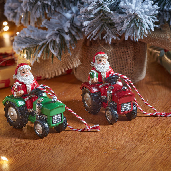 Two Christmas ornament figurines of Santa Claus driving tractor-shaped cars, one green and one red, with red-and-white striped tow ropes
